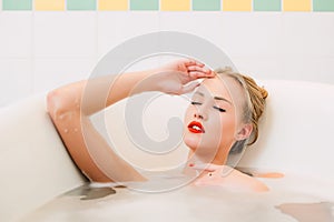 Portrait passionate young caucasian blonde girl lying in white bathroom