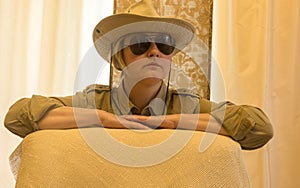 Portrait in pastel shades of attractive Caucasian mature woman wearing shirt, hat and black sunglasses