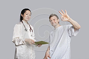 Portrait of patient gesturing okay with doctor holding a clipboard