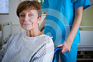 Portrait of patient sitting on wheel chair with nurse standing behind