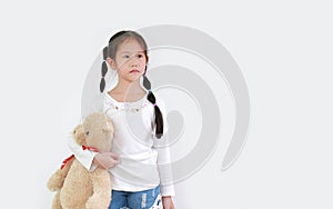 Portrait of peaceful asian little child girl carrying a teddy bear doll isolated on white background with copy space