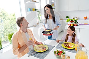 Portrait of peaceful friendly family little girl cheerful parents prepare eat tasty homemade food communicate have good