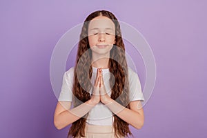 Portrait of peaceful lovely sweet small girl hold palms together yoga lesson on purple background