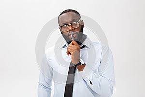 Portrait of a pensive African American businessman in a gray suit thinking with pen on his hand.