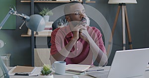 Portrait of pensive African American man entrepreneur thinking looking at laptop screen in office