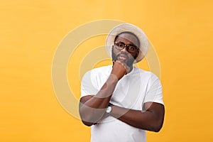 Portrait of a pensive afro american man in glasses looking up at copyspace isolated on a yellow background