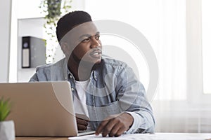 Portrait of pensive afro businessman sitting at workplace in modern office