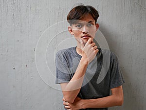 Portrait of pensive Asian man looking into empty space, touching his chin