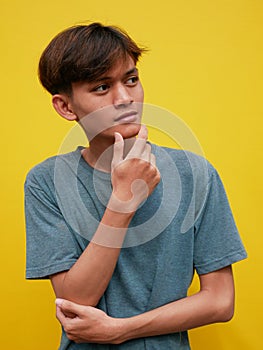 Portrait of pensive Asian man looking into empty space, touching his chin