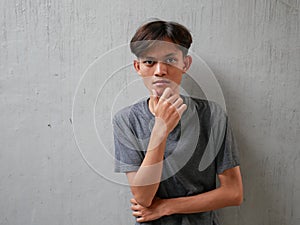 Portrait of pensive Asian man looking into empty space, touching his chin