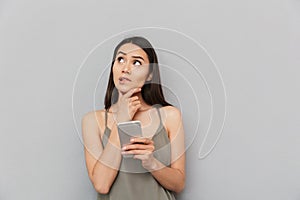 Portrait of a pensive asian woman holding mobile phone