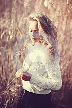 Portrait of pensive beautiful young blonde girl in a field in white pullover, the concept of health and beauty photo