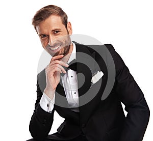 Portrait of pensive businessman in black suit sitting and smiling