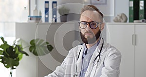 Portrait of pensive caucasian male doctor looking at camera in clinic office