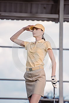 portrait of pensive female golf player in cap with golf club