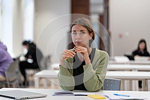 Portrait of pensive focused middle-aged woman mature female student in library interior