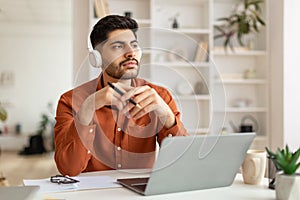 Arab man using laptop sitting at desk in office