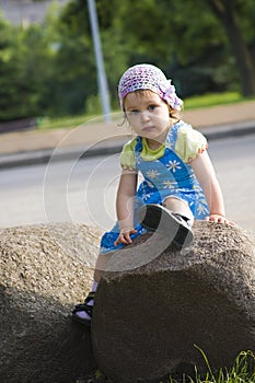 Portrait of pensive girl sitting on a rock