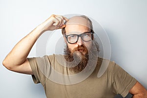 Portrait of pensive male standing holding hand on his head, looking at camera, thoughtful expression