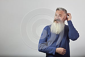 Portrait of pensive mature gray-haired bearded man on gray background, selective focus