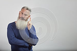 Portrait of pensive mature gray-haired bearded man on gray background, selective focus