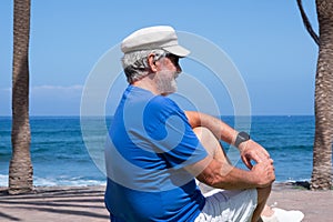 Portrait of pensive senior man at beach looking away. Retired enjoying summer holiday at sea