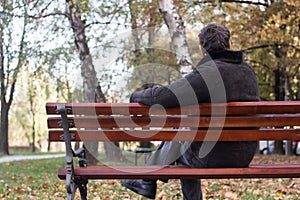 Portrait of a pensive senior man sitting on the bench, in the public park, outdoors
