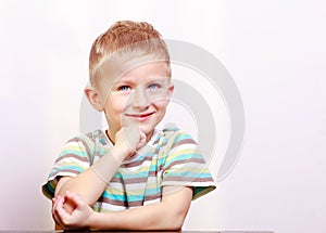 Portrait of pensive smiling blond boy child kid at the table