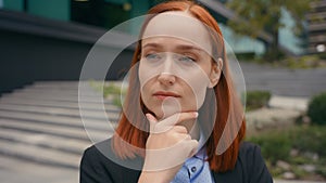 Portrait pensive thinking serious Caucasian ginger hair business woman in city outdoors businesswoman think problem