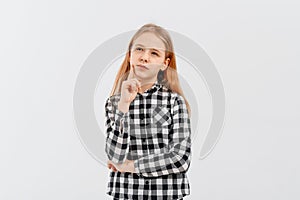 Portrait of a pensive thoughtful pretty teen girl thinking about something, looking aside, standing in casual shirt over white