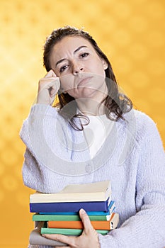 Portrait of pensive woman carrying stack of books, memorizing information photo
