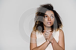 The portrait of a pensive woman looking to the side with crossing arms in front of herself while standing in a studio