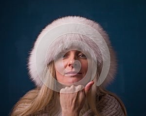 Portrait of pensive woman in warm winter fur hat looking at came