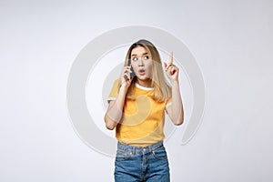 Portrait of a pensive young asian woman holding mobile phone and looking away thinking over white background