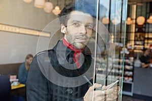 Portrait of pensive young pretty unshaved brunette guy dressed in elegant clothes looking thoughtfully out of window while