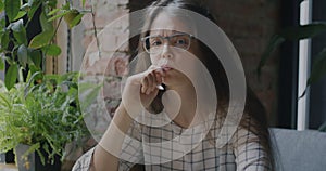 Portrait of pensive young woman artist indoors in cafe sitting alone holding digital tablet pen looking at camera