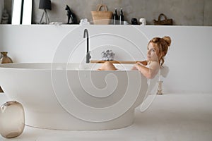 Portrait of pensive young woman taking bath and looking away