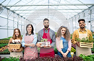 Portrait of people working in greenhouse in garden center, looking at camera.