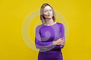 Portrait of perplexed thoughtful woman looking aside with doubting inquiring expression. indoor studio shot isolated on yellow