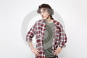 Portrait of perplexed young man in casual clothes looking camera, standing with arms akimbo isolated on white wall