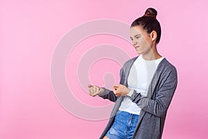 Portrait of persistent brunette teenage girl pretending to pull with big effort. pink background, copy space