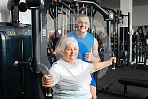 Portrait of person on a simulator in a gym. senior concept, a woman and a coach lead a healthy lifestyle, engage in