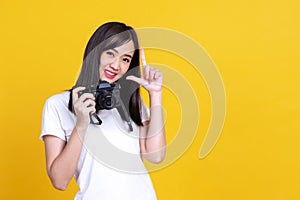 Portrait photo of Asian smiling pretty girl in white shirt taking photo on camera  over orrange background
