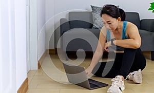 Portrait photo of beautiful adult 40 years old Asian woman in blue color Sports Clothing using Laptop for prepare Home Workout