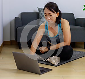 Portrait photo of beautiful adult 40 years old Asian woman in blue color Sports Clothing using Laptop for prepare Home Workout