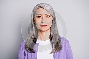 Portrait photo of an calm old lady with long white hair wearing purple cardigan isolated on grey color background