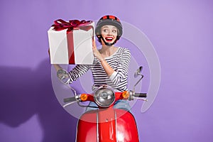 Portrait photo of curious girl on scooter trying to guess what inside big wrapped present box  on bright purple