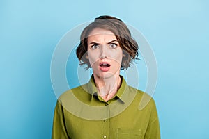 Portrait photo of funny nervous confused girl with short brunette hair wearing green shirt starring surprised with