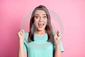 Portrait photo of happy surprised young woman gesturing like winner staring with opened mouth isolated on pastel pink