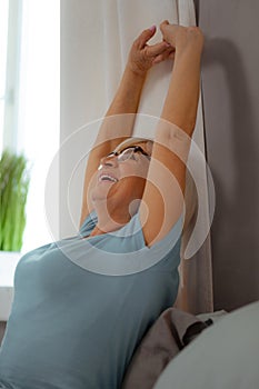 Portrait photo of lady stretching on the bed with sheets.